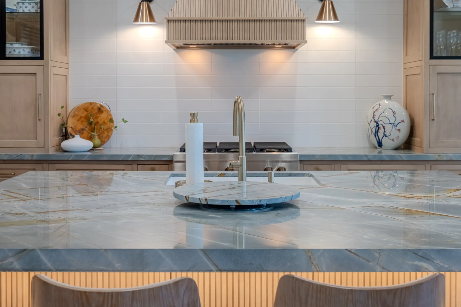 Custom kitchen with fluted illuminated island, wood cabinetry, and integrated glass display cabinets
