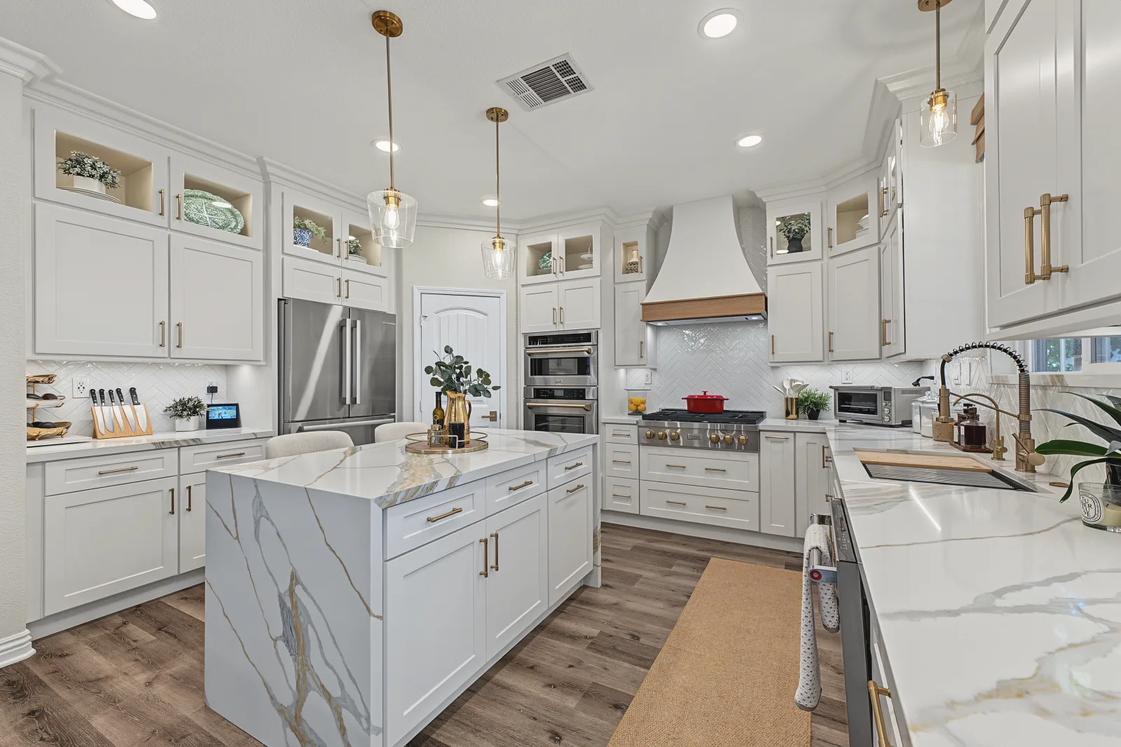 White kitchen with a large island and veined quartz countertops