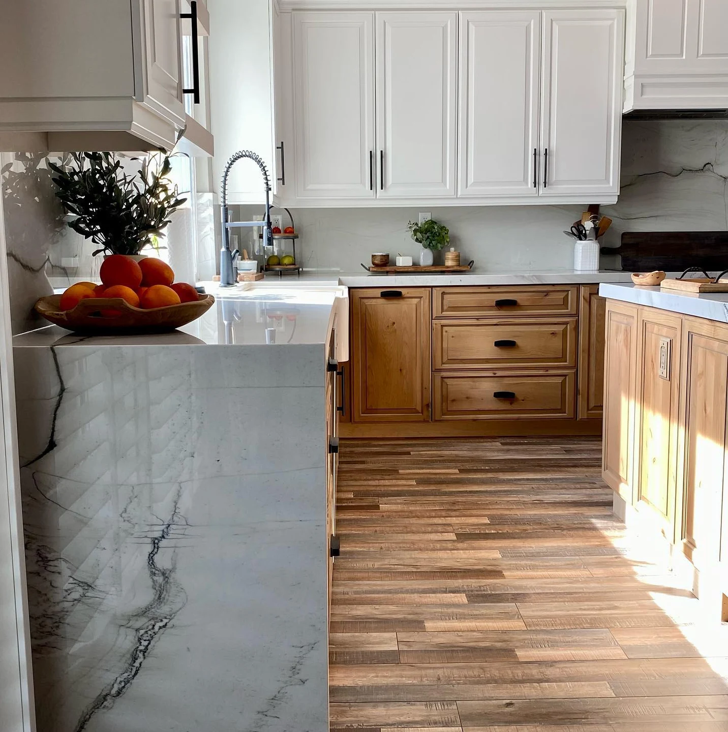 Custom kitchen with natural wood lower cabinetry, white upper cabinets, and light stone counters
