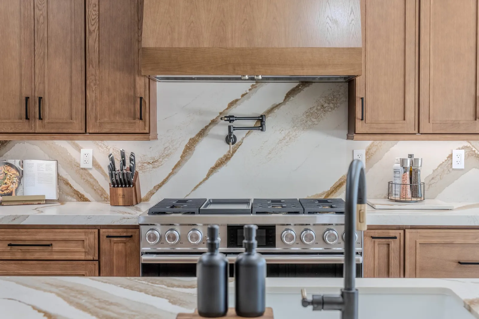Bold veined stone countertops and full-height backsplash with oak cabinets