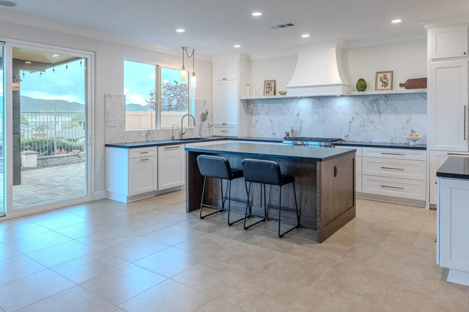White kitchen remodel with dark wood island and full-height stone backsplash