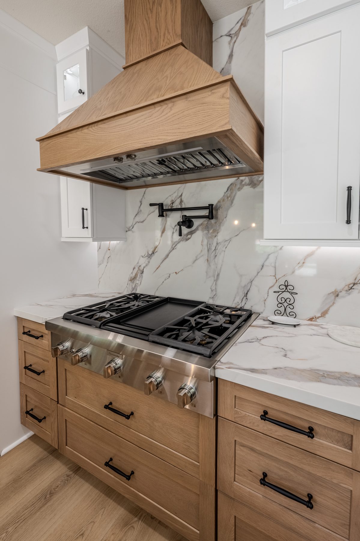 Custom oak range hood with stone countertops and full-height backsplash