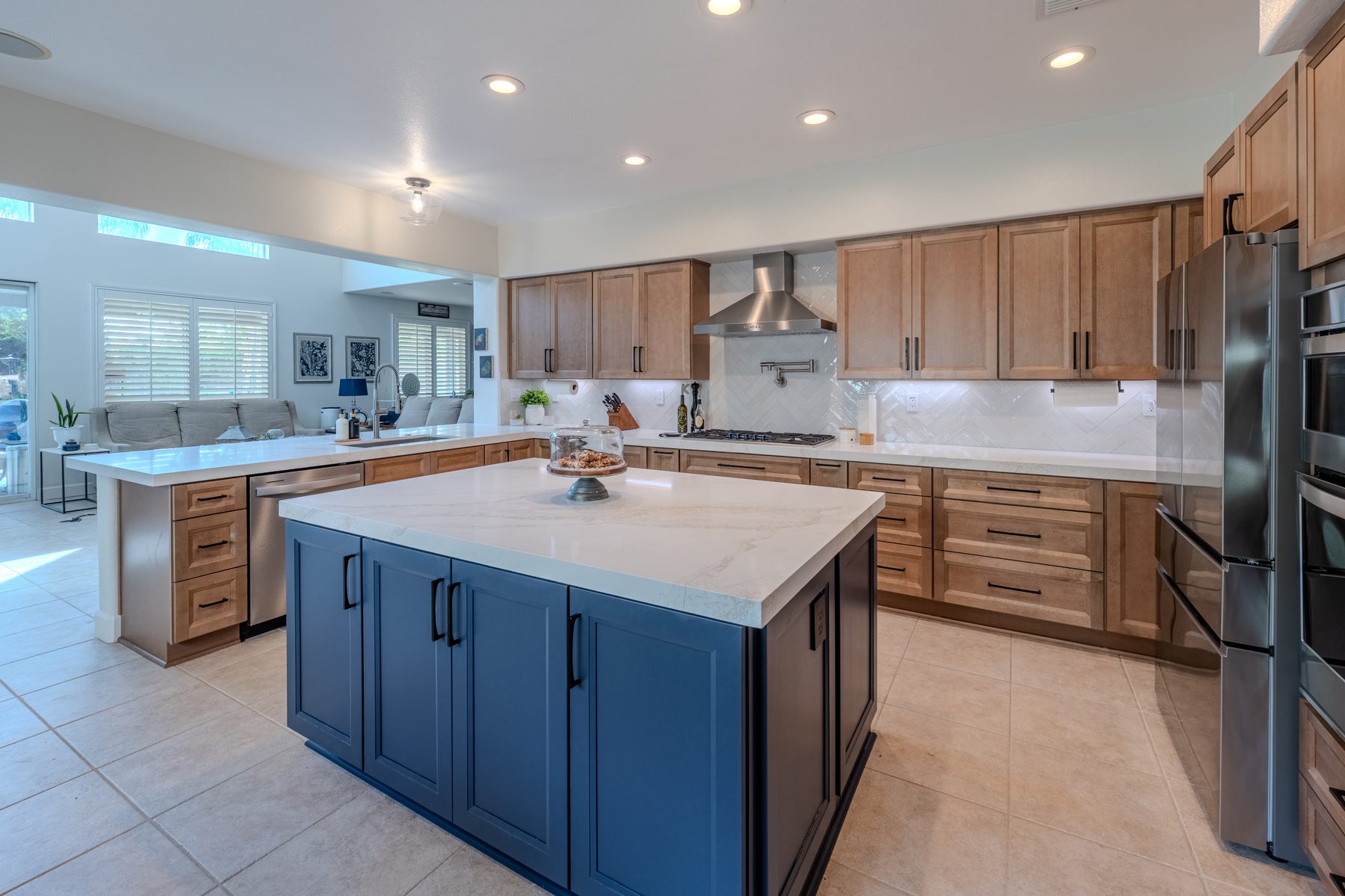 Two-tone kitchen with blue island, wood cabinets, and white countertops